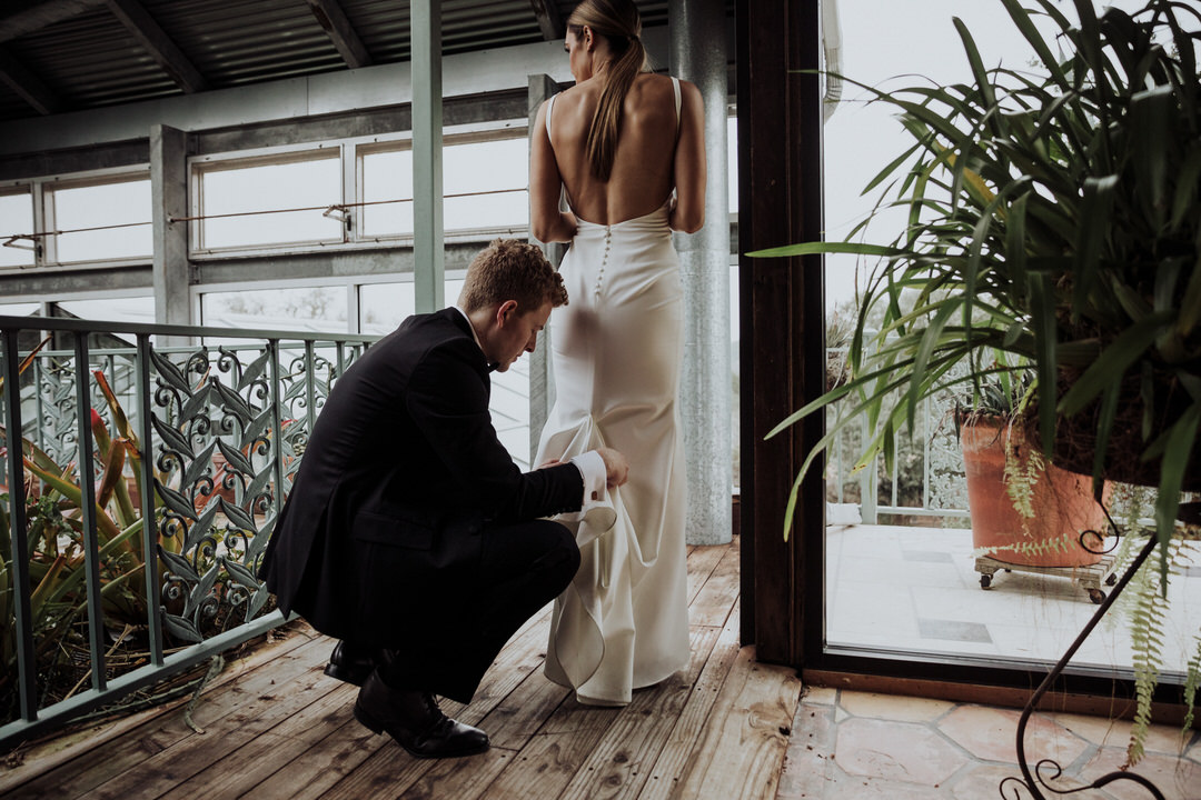 groom helping bride bustle dress