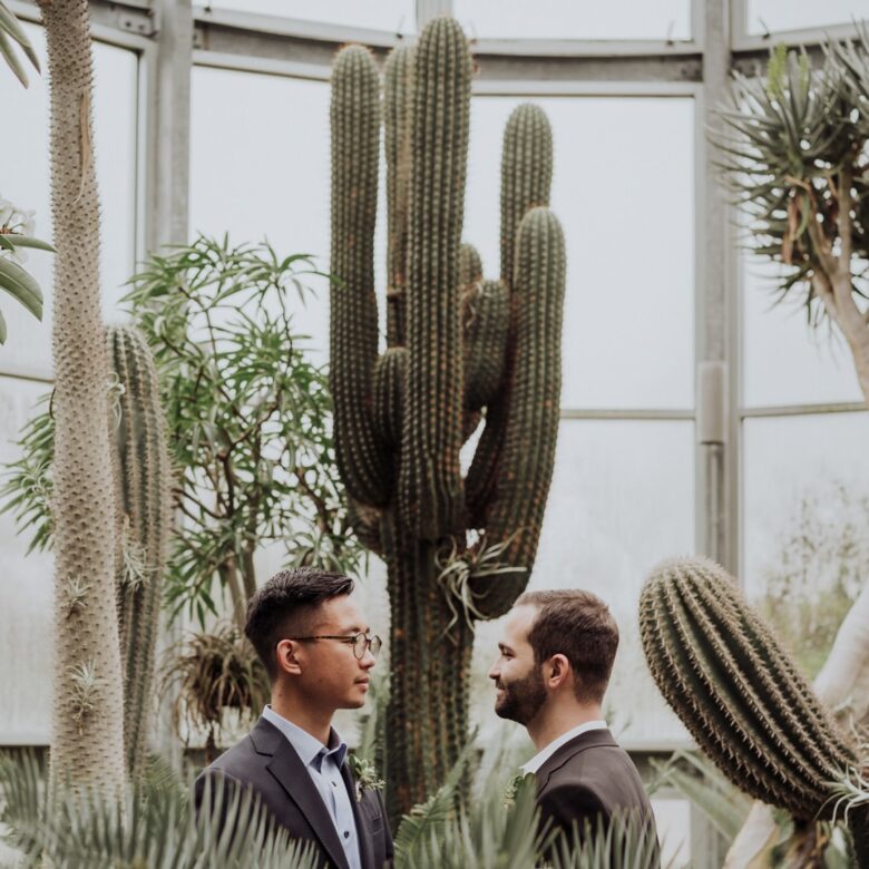 Ethan and Mark’s LGBTQ wedding portraits at The Greenhouse near Austin, photographed among tropical plants and cacti