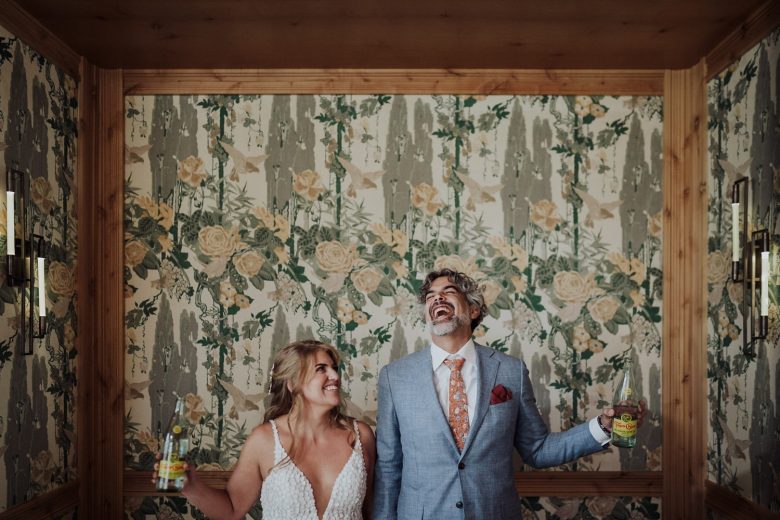 Couple laughing with Topo Chico bottles during their Austin Proper wedding portraits