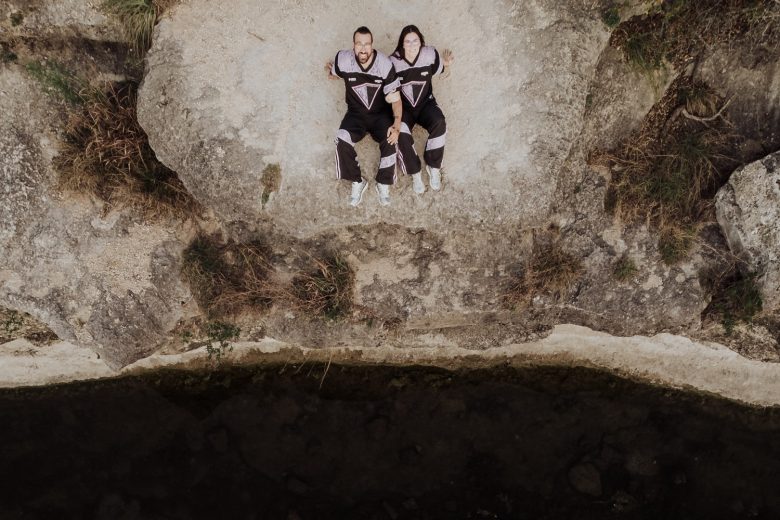 An overhead portrait by an Austin engagement photographer shows Shelby and Clay lying together on limestone beside Bull Creek.