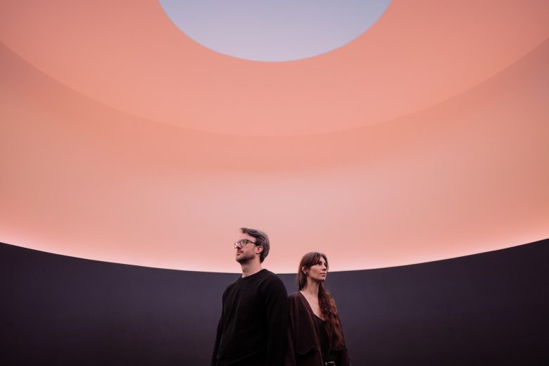Sonia and Paul stand beneath the glowing oval opening of James Turrell's The Color Inside Skyspace in Austin.